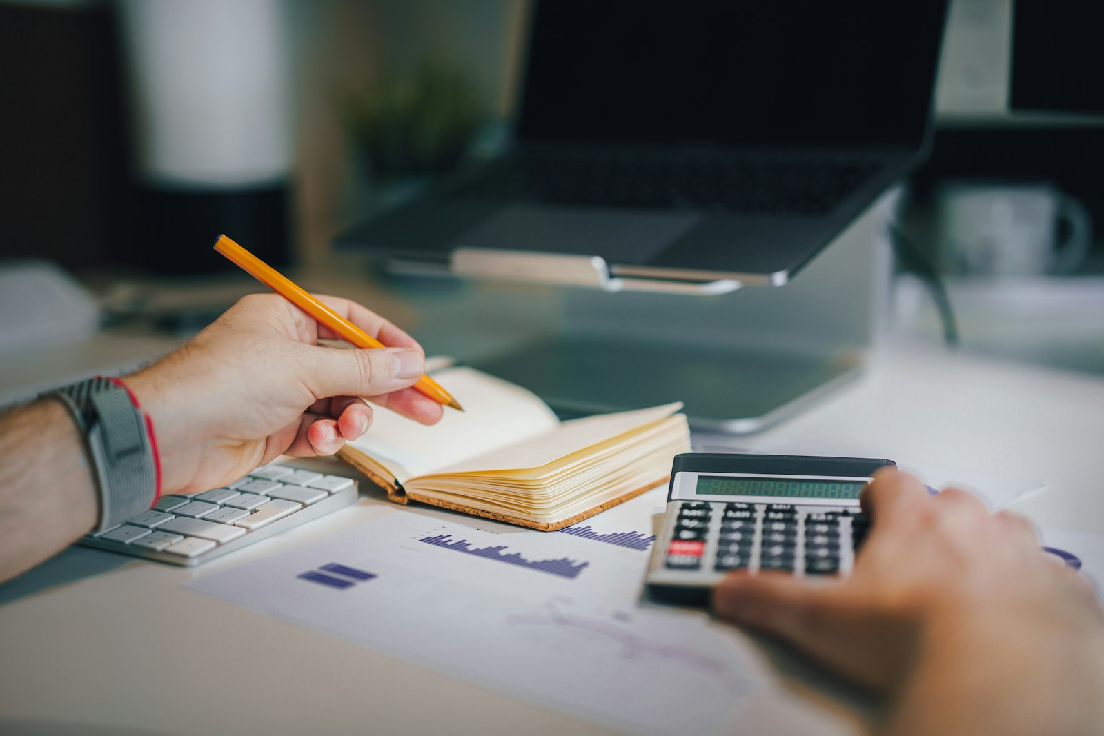A person working through figures with a notebook and a calculator