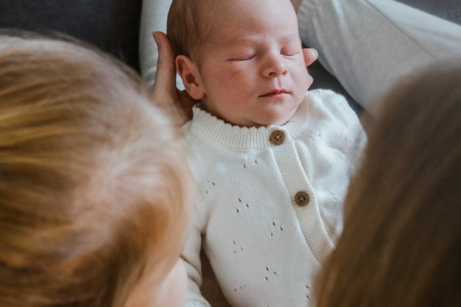A sleeping newborn baby lying between two older siblings