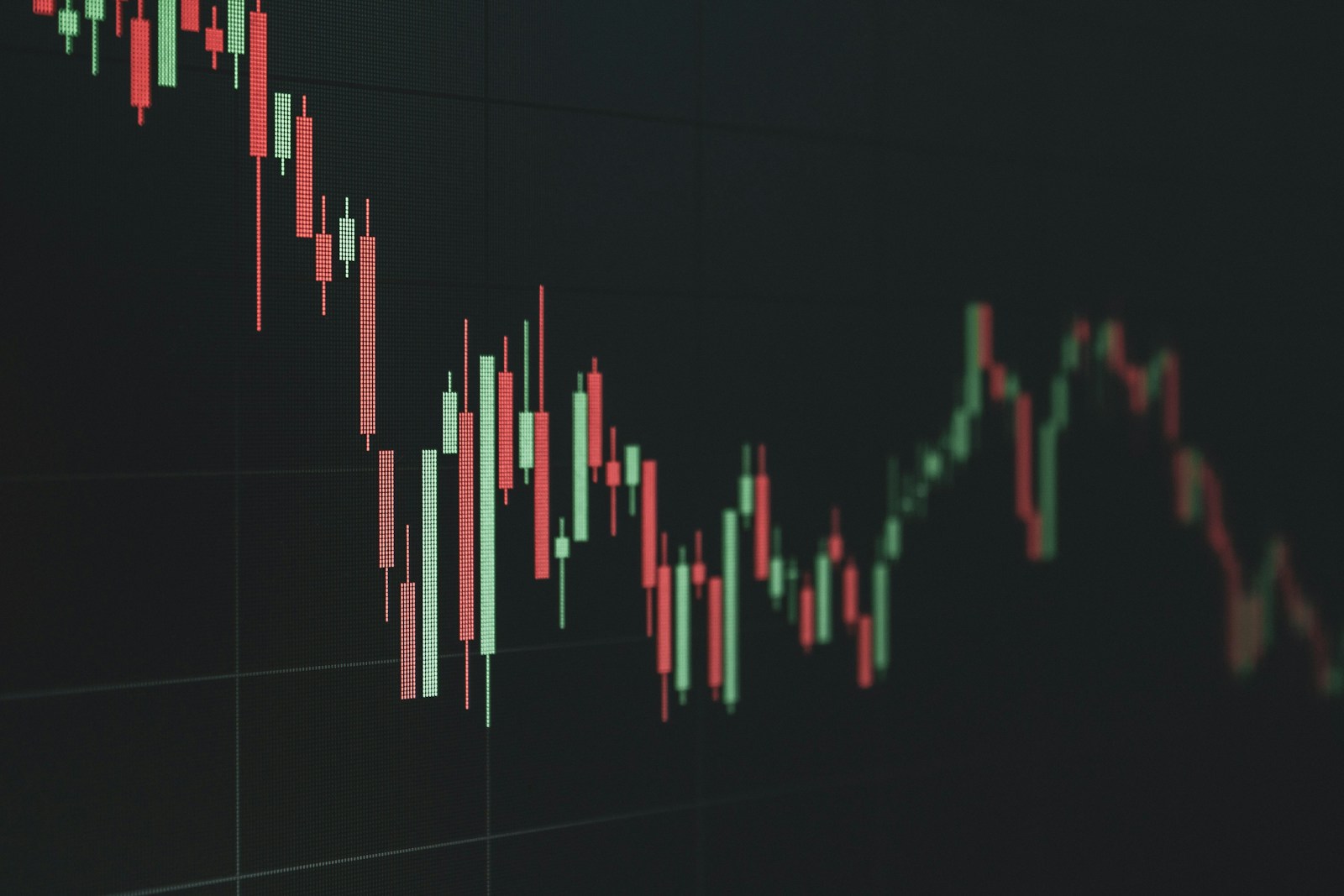 A candlestick market chart trending downwards on a dark screen