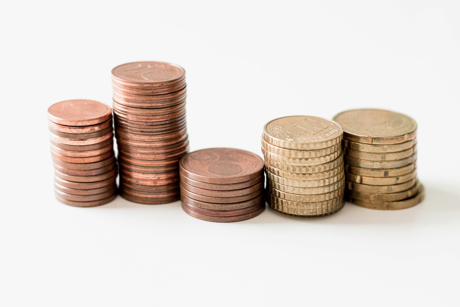 Five stacks of copper and brass coins on a white surface