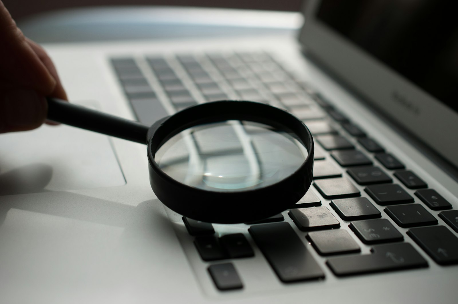 A magnifying glass held over a laptop keyboard