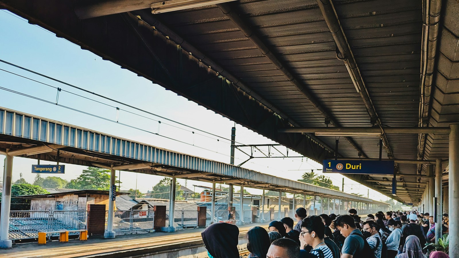 Commuters waiting in a queue along a covered train platform