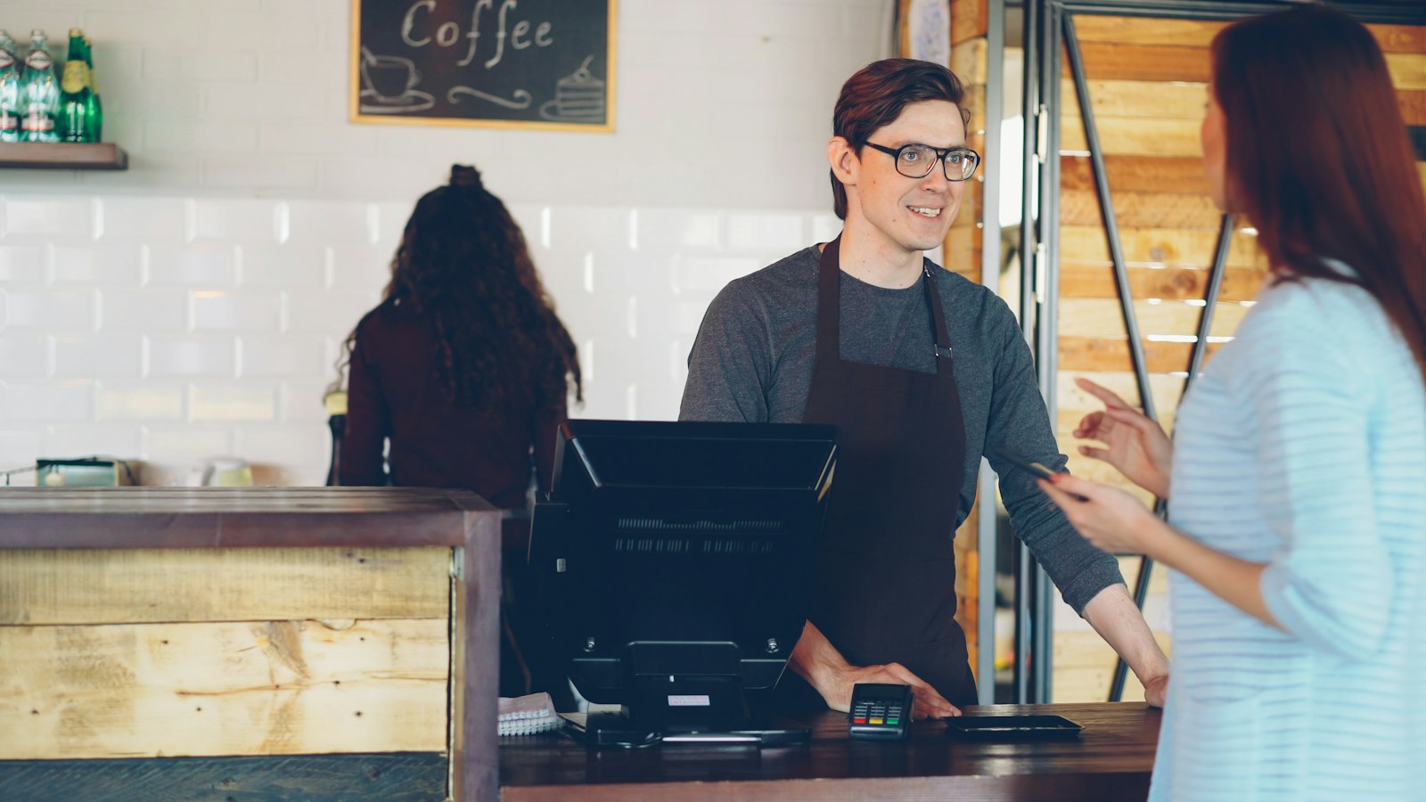 A customer paying at a coffee shop counter