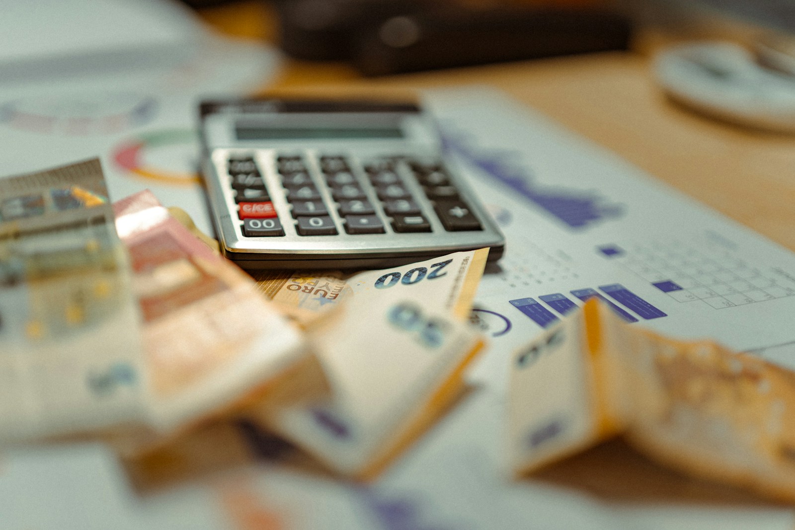 Banknotes and a calculator resting on printed financial charts