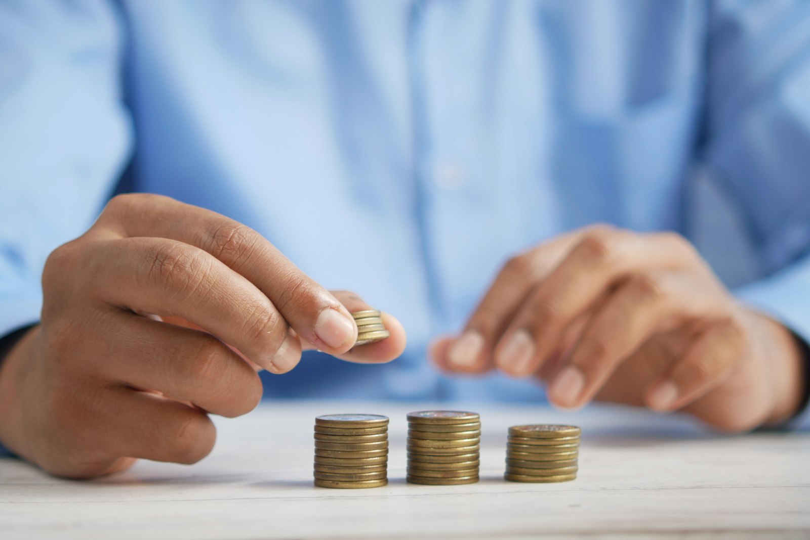 A person building three stacks of coins on a table
